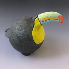 a black vase with a yellow and blue toucan on it's head