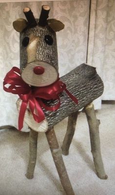 a wooden reindeer with a red ribbon around its neck and nose sitting on top of a piece of wood