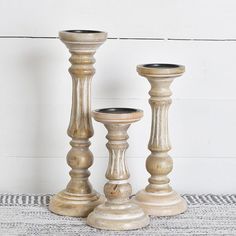 three wooden candlesticks sitting next to each other on top of a white table