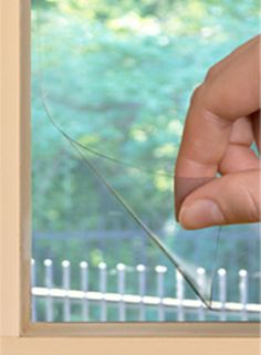 a hand holding a piece of glass in front of a window