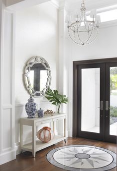 a room with a table, mirror and vases on the floor in front of it