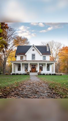 a white house in the fall with leaves on the ground and trees around it's edges