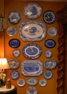 blue and white plates hanging on the wall next to a table with a lamp in front of it