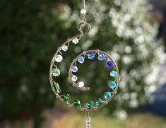 a wind chime with beads hanging from it's side in front of a tree