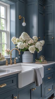 a kitchen with blue cabinets and white flowers in a vase on the sink countertop