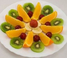 a white plate topped with sliced fruit and kiwis on top of each other