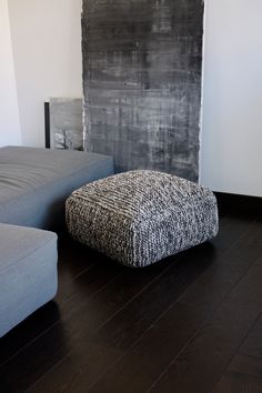 a living room with two gray couches next to a black and white painting on the wall