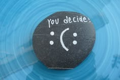 a rock with the words you decide written on it in front of a blue background