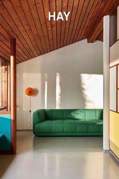 a green couch sitting under a wooden ceiling