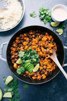 a skillet filled with black beans, rice and avocado garnished with cilantro