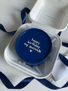 a blue birthday cake in a white box with writing on the lid and ribbon around it