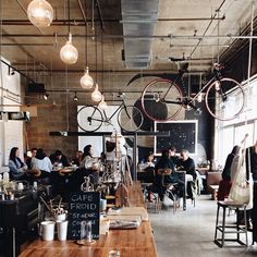 an image of people sitting at tables with bicycles hanging from the ceiling