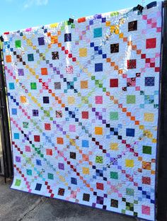 a colorful quilt is hanging on a fence