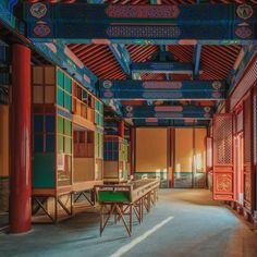 an empty room with tables and chairs in the center, surrounded by red pillars on either side