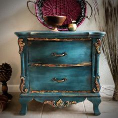 a blue dresser with gold trimmings and an ornate basket on top of it