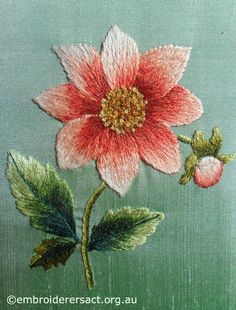 a pink flower with green leaves on a light blue background is embroidered onto a piece of fabric