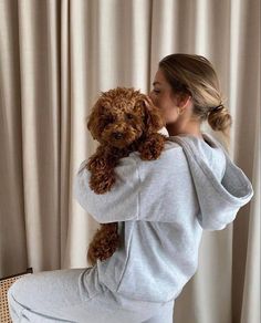 a woman sitting on a chair holding a brown dog in her arms and looking at the camera