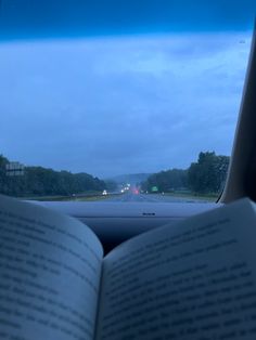 an open book sitting in the passenger seat of a car on a highway at night