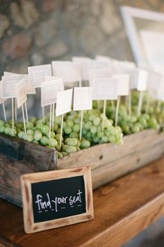 a wooden crate filled with green grapes on top of a table next to a chalkboard