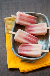 three popsicles sitting on top of a metal plate next to a yellow napkin and fork