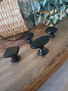 three black knobs on a wooden table next to a basket with flowers in it