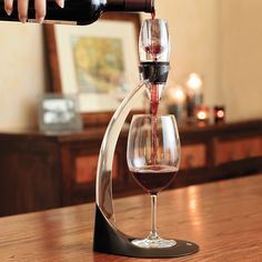 a person pouring wine into a glass on top of a wooden table