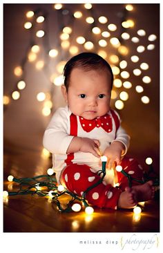 a baby sitting on the floor with some lights around her and looking at the camera