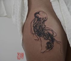 a black and white photo of a jellyfish on the back of a woman's thigh