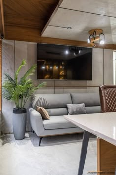 a living room with a couch, table and television mounted to the wall above it