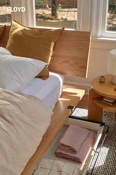 a bed sitting next to a window in a room with wooden furniture and pillows on top of it