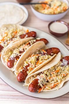 there are four hotdogs on the plate with coleslaw and other toppings