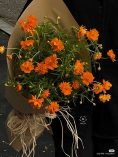 a person holding a bouquet of orange flowers