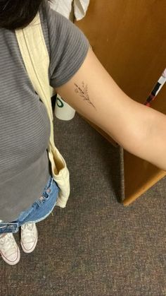 a woman with a tattoo on her arm is sitting in front of a desk and holding a pen