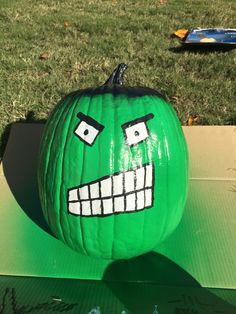 a green pumpkin with a face painted on it