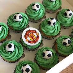 cupcakes with green frosting and soccer balls on top are in a box