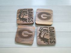 four wooden coasters with the logos of three different teams