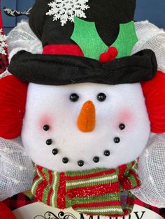 a snowman is wearing a black hat and green scarf