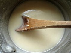 a wooden spoon in a pot filled with milk and liquid on top of a table