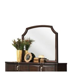 a wooden dresser topped with a mirror and vase