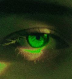 a close up view of an eye with green light shining on it's iris