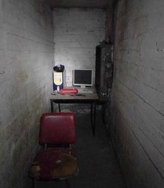 an empty room with two red chairs and a computer