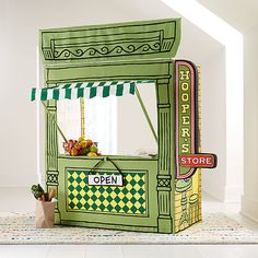 a small green and yellow food cart sitting on top of a white floor next to a window