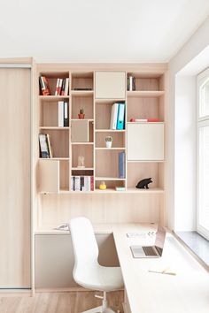 a white chair sitting in front of a wooden book shelf