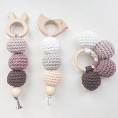 three crocheted toys are arranged on a white surface, one is wooden and the other is plastic