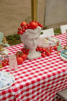 a table topped with plates and bowls filled with tomatoes on top of a checkered table cloth