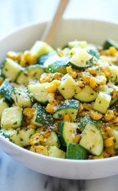 a white bowl filled with zucchini and corn salad on top of a marble counter