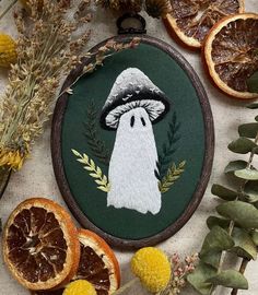 a cross stitch ornament with an image of a ghost surrounded by dried oranges