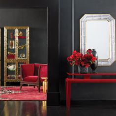 a living room with black walls and red furniture in the corner, along with a gold framed mirror on the wall