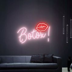 a black couch sitting in front of a neon sign that says botox on it