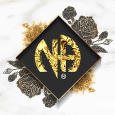 the logo is made up of gold foil and black flowers on a white marble background